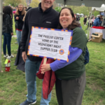 Mares Beauvais standing in the countryside with a sign reading "the paulist center: home of the wednesday night supper club"